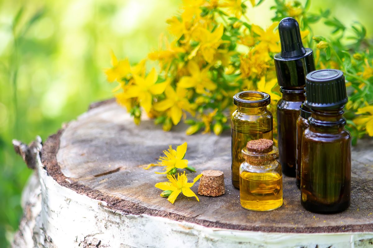 Bottles of essential oil and yellow flowers on a wood slice